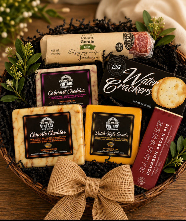 Bravo's Gold gift basket - three Vintage Cheese Company cheeses, Busseto dry salami, Elki water crackers and a Hammond's chocolate bar in a wicker basket with burlap bow